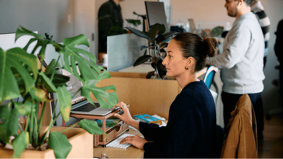 A teammate working at her desk among the office plants