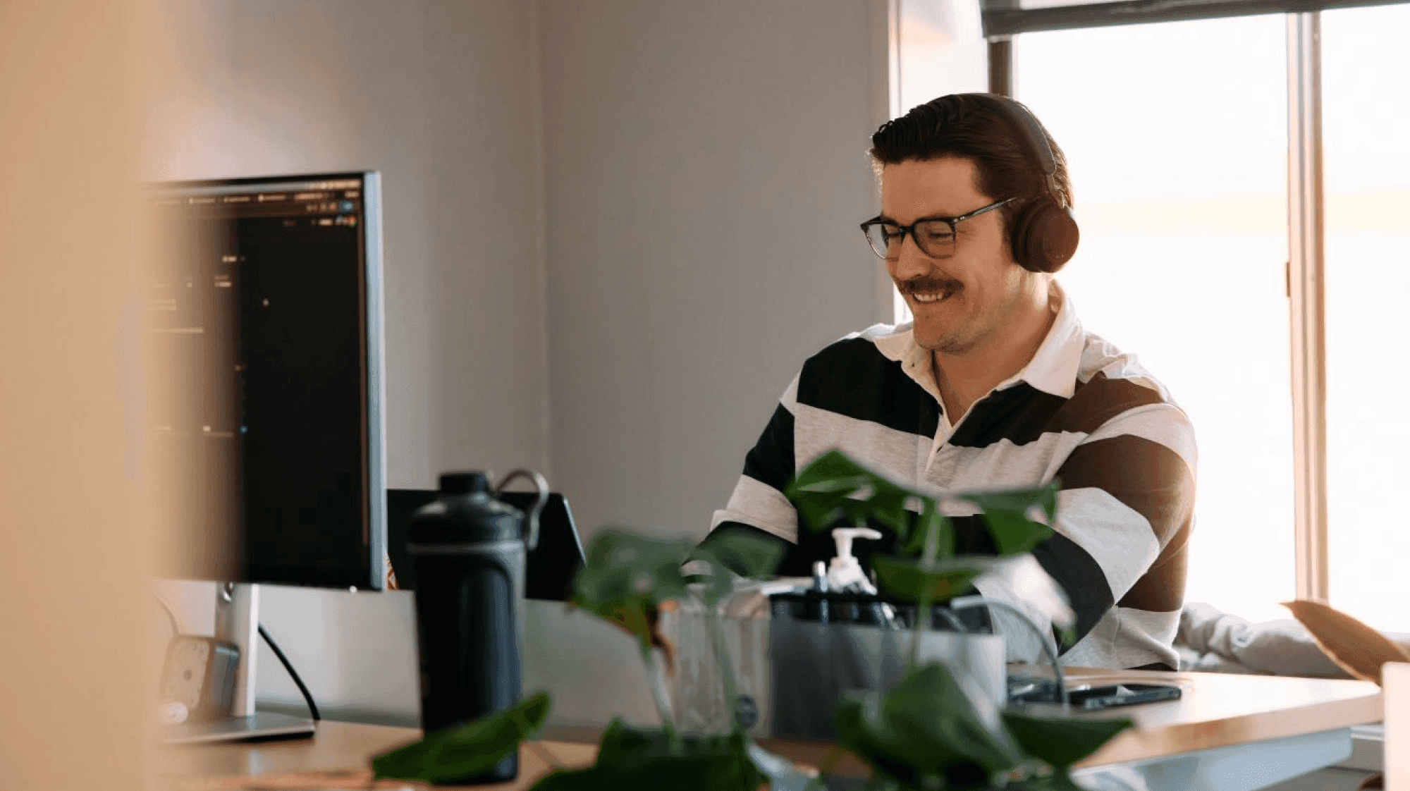 An engineer wearing headphones working at his monitor